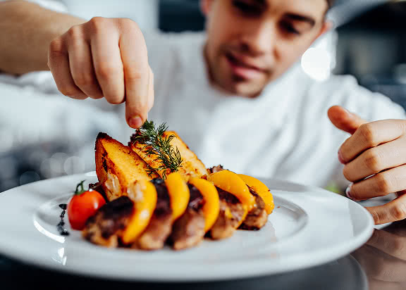A chef with some orange fruit on a plate